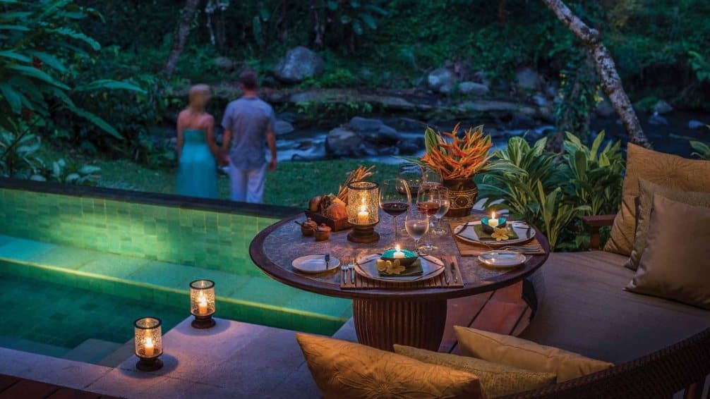Couple walking past a candlelit poolside dinner at a luxury resort